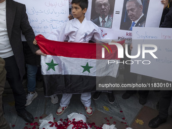 A young Iranian protester holds a Syrian flag while standing behind packages wrapped in shrouds symbolizing the bodies of people of Syria du...