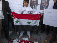 A young Iranian protester holds a Syrian flag while standing behind packages wrapped in shrouds symbolizing the bodies of people of Syria du...