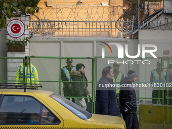 Iranian people walk past policemen guarding the Turkish embassy during a protest against Turkish President Recep Tayyip Erdogan and his dipl...