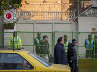 Iranian people walk past policemen guarding the Turkish embassy during a protest against Turkish President Recep Tayyip Erdogan and his dipl...