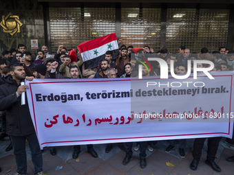 Iranian protesters hold a flag of Syria and an anti-Turkish placard while taking part in a protest against Turkish President Recep Tayyip Er...