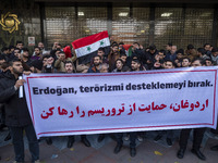 Iranian protesters hold a flag of Syria and an anti-Turkish placard while taking part in a protest against Turkish President Recep Tayyip Er...