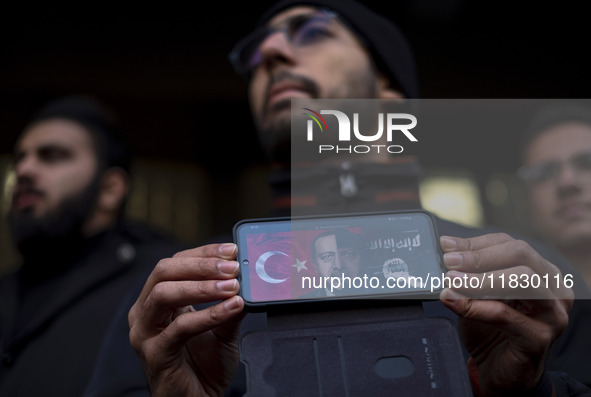 An Iranian protester holds a cellphone featuring an anti-Turkish President poster while participating in a protest against Turkish President...