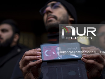 An Iranian protester holds a cellphone featuring an anti-Turkish President poster while participating in a protest against Turkish President...