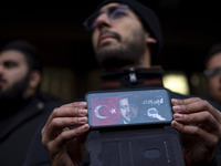 An Iranian protester holds a cellphone featuring an anti-Turkish President poster while participating in a protest against Turkish President...