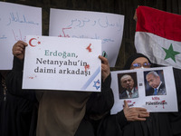 Iranian female protesters hold a flag of Syria and anti-Turkish President placards during a protest against Turkish President Recep Tayyip E...