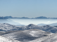 Snow-dusted rolling hills stretch toward distant mist-covered peaks in Campo Imperatore, Gran Sasso d'Italia, Italy, on November 16, 2024....