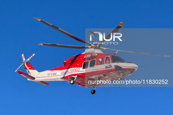 A rescue helicopter from Vigili del Fuoco hovers in a clear blue sky above Campo Imperatore, Gran Sasso d'Italia, Italy, on November 16, 202...