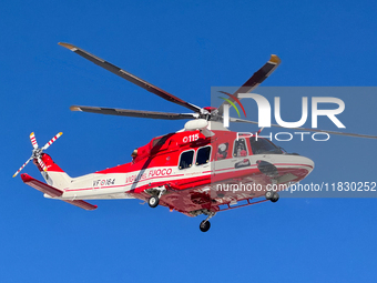 A rescue helicopter from Vigili del Fuoco hovers in a clear blue sky above Campo Imperatore, Gran Sasso d'Italia, Italy, on November 16, 202...