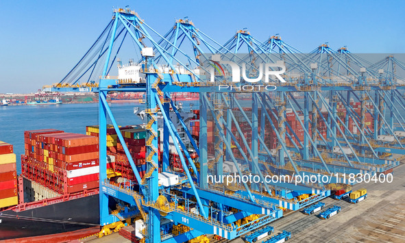 A cargo ship loads and unloads cargo at the fully automated terminal of Qingdao Port in Qingdao, China, on December 3, 2024. 