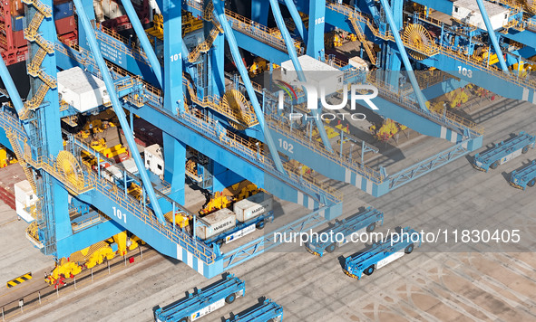 An automatic guided vehicle waits to deliver goods under a bridge crane at a fully automated terminal in Qingdao Port in Qingdao, China, on...