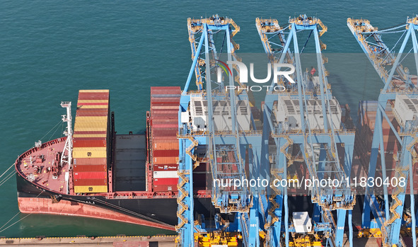 A cargo ship loads and unloads cargo at the fully automated terminal of Qingdao Port in Qingdao, China, on December 3, 2024. 