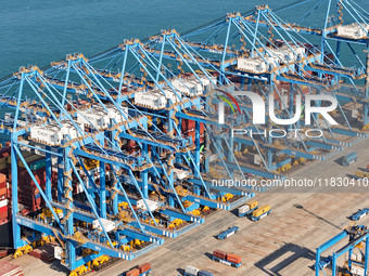 A cargo ship loads and unloads cargo at the fully automated terminal of Qingdao Port in Qingdao, China, on December 3, 2024. (