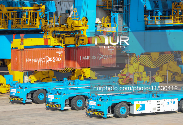 An automatic guided vehicle waits to deliver goods under a bridge crane at a fully automated terminal in Qingdao Port in Qingdao, China, on...