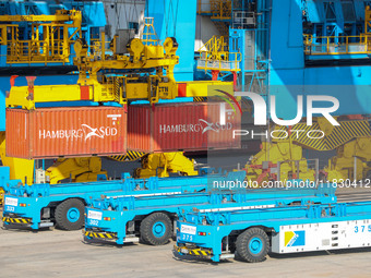 An automatic guided vehicle waits to deliver goods under a bridge crane at a fully automated terminal in Qingdao Port in Qingdao, China, on...