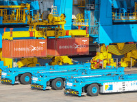 An automatic guided vehicle waits to deliver goods under a bridge crane at a fully automated terminal in Qingdao Port in Qingdao, China, on...