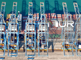 A cargo ship loads and unloads cargo at the fully automated terminal of Qingdao Port in Qingdao, China, on December 3, 2024. (