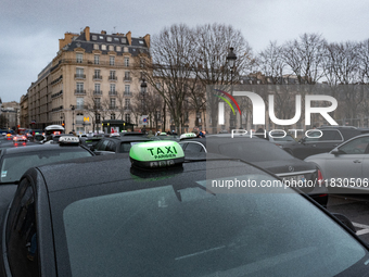 Taxi drivers gather at the Invalides in Paris, France, on December 3, 2024, during a demonstration against a new downward pricing system for...