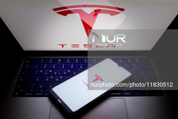 The Tesla logo appears on a smartphone screen and on a computer screen in this photo illustration in Athens, Greece, on December 3, 2024. (P...