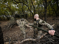 An artilleryman of the Khyzhak Patrol Police Special Unit cleans the barrel of a howitzer while on a combat mission at the positions in Done...