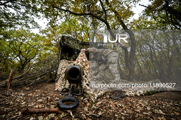 An artilleryman of the Khyzhak Patrol Police Special Unit covers a howitzer with a camouflage net while on a combat mission at the positions...