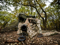 An artilleryman of the Khyzhak Patrol Police Special Unit covers a howitzer with a camouflage net while on a combat mission at the positions...