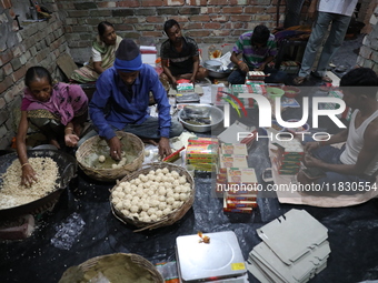 Workers prepare ''Joynagar Moa of West Bengal,'' an Indian sweet made with folk rice mixed with date molasses, inside a workshop at Jayanaga...