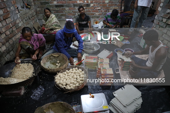 Workers prepare ''Joynagar Moa of West Bengal,'' an Indian sweet made with folk rice mixed with date molasses, inside a workshop at Jayanaga...