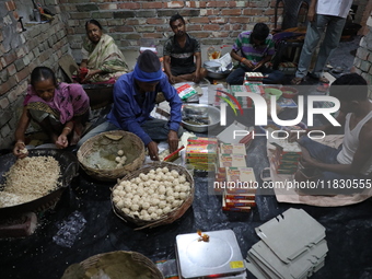 Workers prepare ''Joynagar Moa of West Bengal,'' an Indian sweet made with folk rice mixed with date molasses, inside a workshop at Jayanaga...