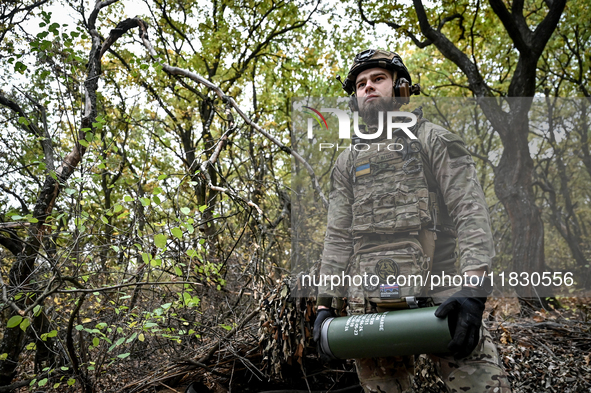 An artilleryman of the Khyzhak Patrol Police Special Unit holds an artillery shell case while on a combat mission at the positions in the Do...