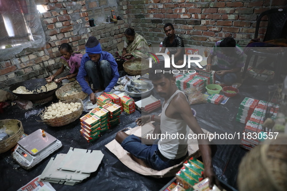 Workers prepare ''Joynagar Moa of West Bengal,'' an Indian sweet made with folk rice mixed with date molasses, inside a workshop at Jayanaga...