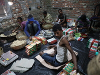 Workers prepare ''Joynagar Moa of West Bengal,'' an Indian sweet made with folk rice mixed with date molasses, inside a workshop at Jayanaga...