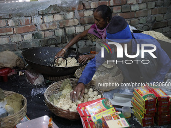 Workers prepare ''Joynagar Moa of West Bengal,'' an Indian sweet made with folk rice mixed with date molasses, inside a workshop at Jayanaga...