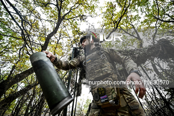 An artilleryman of the Khyzhak Patrol Police Special Unit holds an artillery shell case while on a combat mission at the positions in the Do...