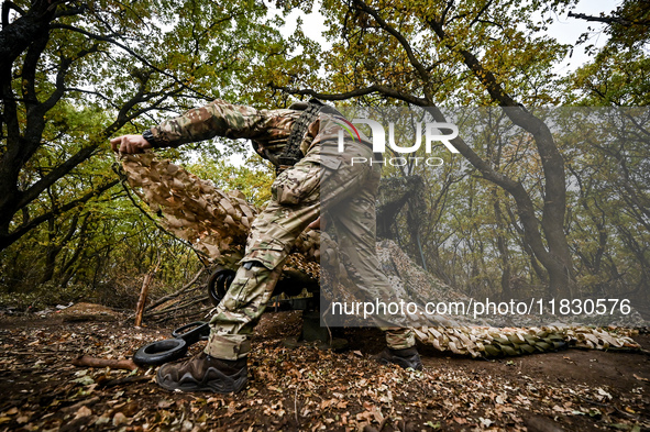 An artilleryman of the Khyzhak Patrol Police Special Unit covers a howitzer with a camouflage net while on a combat mission at the positions...