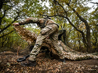 An artilleryman of the Khyzhak Patrol Police Special Unit covers a howitzer with a camouflage net while on a combat mission at the positions...