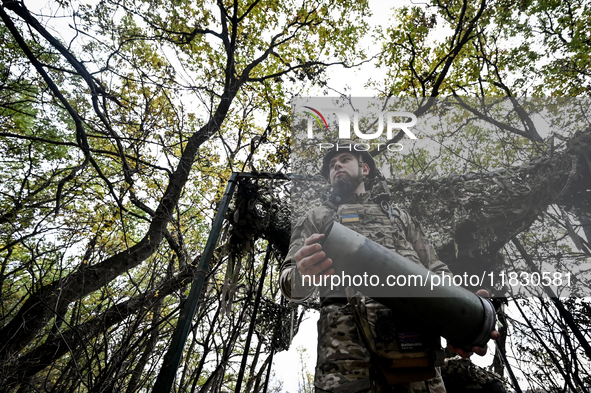 An artilleryman of the Khyzhak Patrol Police Special Unit holds an artillery shell case while on a combat mission at the positions in the Do...