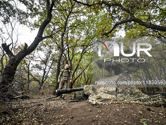 An artilleryman of the Khyzhak Patrol Police Special Unit stands by a howitzer covered with a camouflage net while on a combat mission at th...