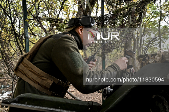 An artilleryman of the Khyzhak Patrol Police Special Unit speaks through a handheld transceiver as he tunes a howitzer while on a combat mis...