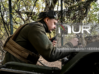 An artilleryman of the Khyzhak Patrol Police Special Unit speaks through a handheld transceiver as he tunes a howitzer while on a combat mis...