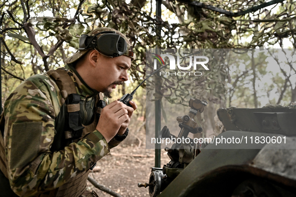 An artilleryman of the Khyzhak Patrol Police Special Unit speaks through a handheld transceiver as he tunes a howitzer while on a combat mis...