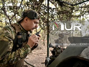 An artilleryman of the Khyzhak Patrol Police Special Unit speaks through a handheld transceiver as he tunes a howitzer while on a combat mis...