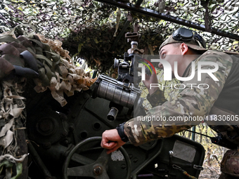 An artilleryman of the Khyzhak Patrol Police Special Unit aims a howitzer while on a combat mission at the positions in Donetsk region, east...