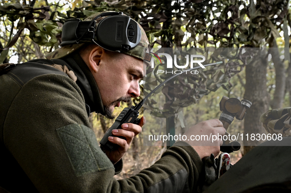 An artilleryman of the Khyzhak Patrol Police Special Unit speaks through a handheld transceiver as he tunes a howitzer while on a combat mis...