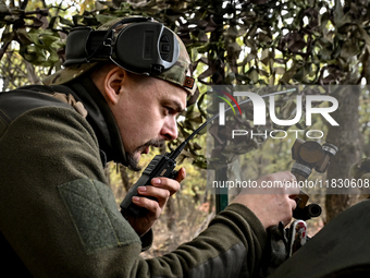 An artilleryman of the Khyzhak Patrol Police Special Unit speaks through a handheld transceiver as he tunes a howitzer while on a combat mis...