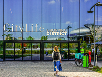 A woman stands in front of an entrance to the CityLife Shopping District in Milan, Italy, on May 27, 2023. (