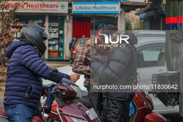 An Indian security personnel checks the identity cards of motorcyclists during a gun battle between militants and security forces on the out...