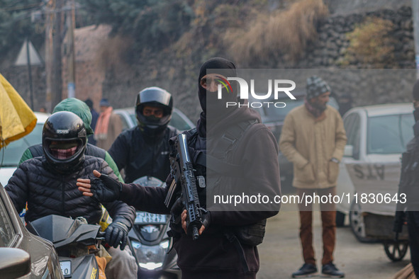 An Indian security personnel guards a road during a gun battle between militants and security forces on the outskirts of Srinagar, Jammu and...