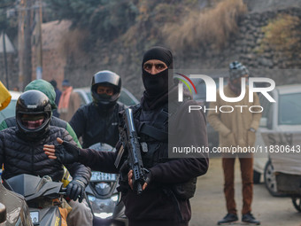 An Indian security personnel guards a road during a gun battle between militants and security forces on the outskirts of Srinagar, Jammu and...