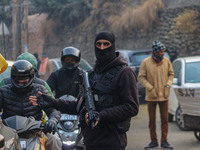 An Indian security personnel guards a road during a gun battle between militants and security forces on the outskirts of Srinagar, Jammu and...